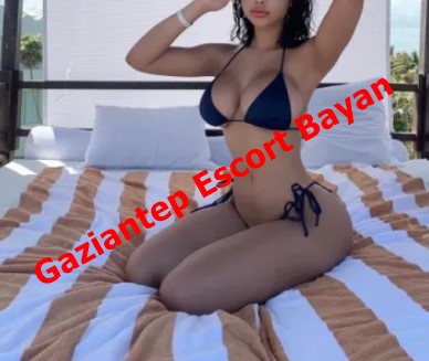 Woman in a navy bikini kneels on a striped bed in a sunlit room, with red text overlay advertising Gaziantep Escort Bayan across the image.
